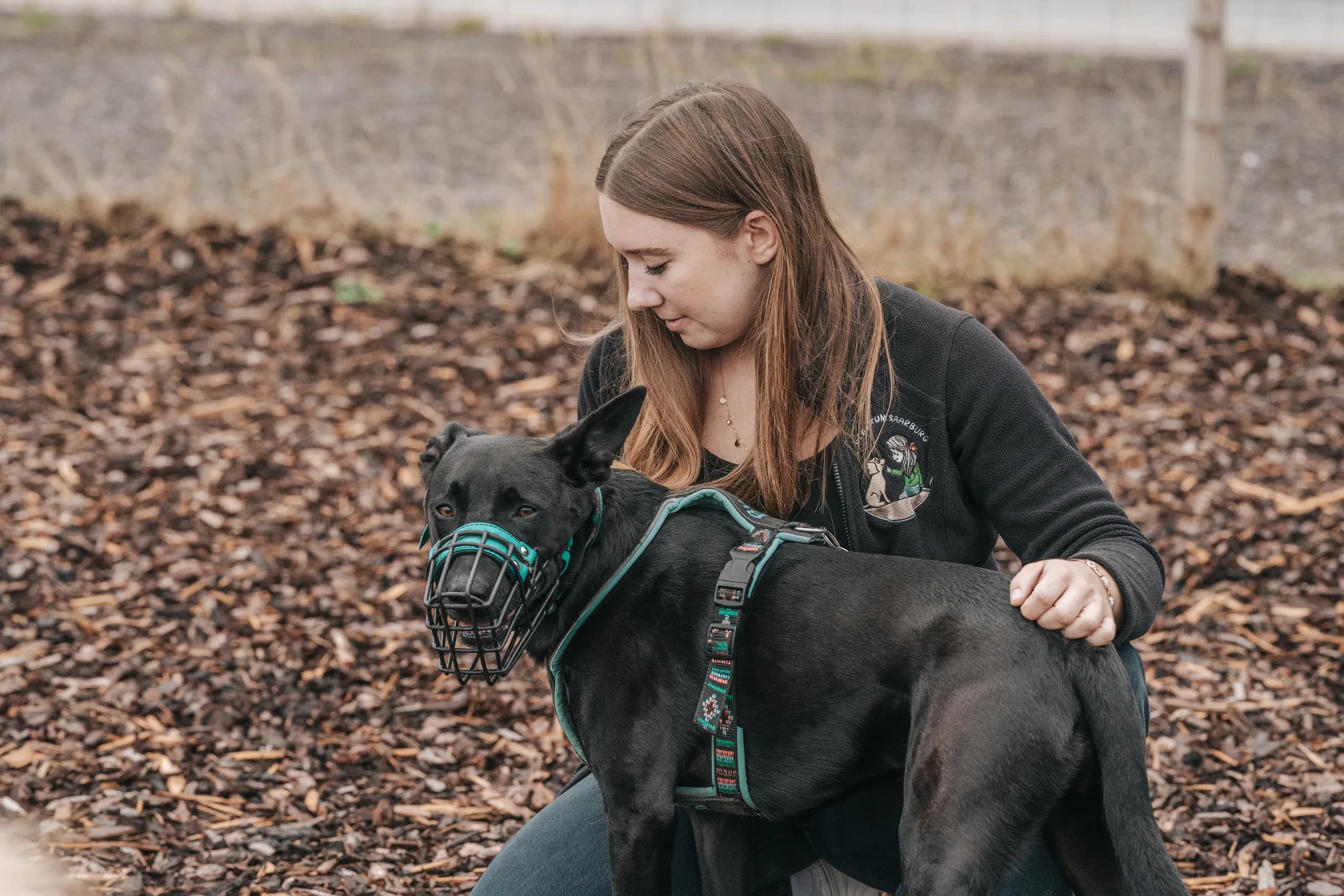 Trainerin übt auf dem Außengelände mit einem schwarzen Hund